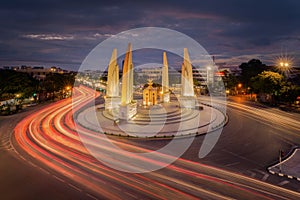 Aerial view of Democracy monument, a roundabout, with car light trails on busy street road in Bangkok Downtown skyline, urban city