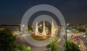 Aerial view of Democracy monument, a roundabout, with car light trails on busy street road in Bangkok Downtown skyline, urban city