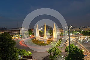 Aerial view of Democracy monument, a roundabout, with car light trails on busy street road in Bangkok Downtown skyline, urban city