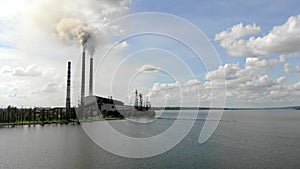 Aerial view Dense thick smoke comes from industrial pipes Against the blue sky and nature and a large lake