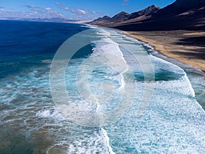 Aerial view on difficult to access golden sandy Cofete beach hidden behind mountain range on Fuerteventura, Canary islands, Spain