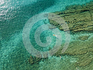 Aerial view of a dinghy in the water floating on a transparent sea. Bathers at sea. Zambrone, Calabria, Italy