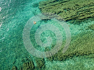 Aerial view of a dinghy in the water floating on a transparent sea. Bathers at sea. Zambrone, Calabria, Italy