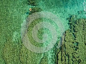 Aerial view of a dinghy in the water floating on a transparent sea. Bathers at sea. Zambrone, Calabria, Italy