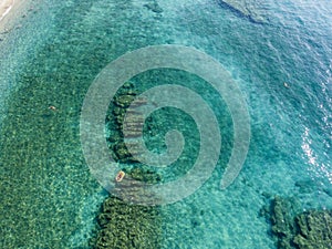 Aerial view of a dinghy in the water floating on a transparent sea. Bathers at sea. Zambrone, Calabria, Italy