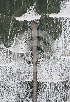 Aerial view directly above Saltburn Pier with rolling waves