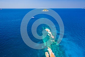 Aerial view of a dive boat near a narrow tropical coral reef and small island in the Andaman Sea