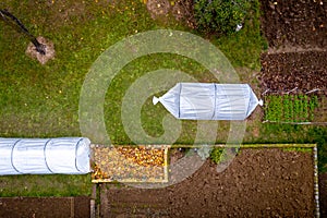 Aerial view of DIY low tunnel greenhouse in a home garden. Polytunnel, autumn garden, cold weather crop protection.