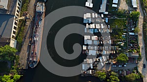 Aerial view of dock on the river with boats on one side of the river. A large cargo ship on the other side of the river