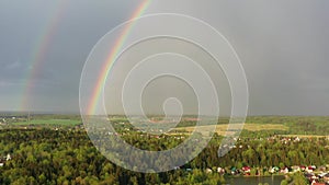 Aerial view of a double rainbow in the sky during rain, rainbow over villages and green fields