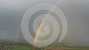 aerial view of a double rainbow in the sky during rain,rainbow over villages and green fields