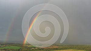 aerial view of a double rainbow in the sky during rain,rainbow over villages and green fields