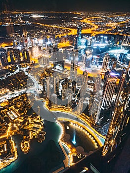 Aerial view of Downtown Dubai with roads, Dubai Mall and the fountain by night, from Burj Khalifa observatory deck in