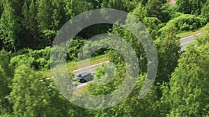 Aerial view of a driving car on the road in a field in sunny weather