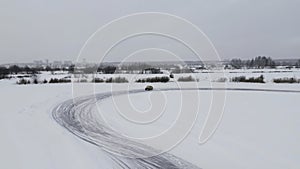 Aerial view of a driving car at snowy track at winter. Clip. One car driving through ice covered lake.