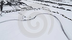 Aerial view of a driving car at snowy track at winter. Clip. One car driving through ice covered lake.