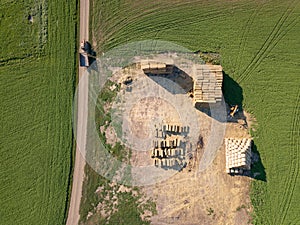 Aerial view from drone into area with stacks of straw after harvesting the grain and dirty road with tractor on it.