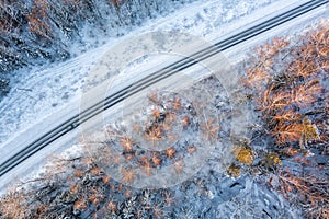 Aerial view from drone of car on curvy snow covered road in the winter forest