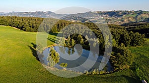 Aerial view of a little lake and trees surrounding, in italian Appennini hills