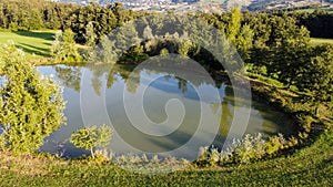 Aerial view of a little lake and trees surrounding, in italian Appennini hills