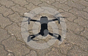 Aerial view on drone shadow on concrete ground, Quadcopter during landing procedure in sunny day