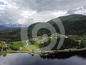 Aerial view, drone shot of Norwegian fjord mountains with green pines and private houses