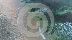 Aerial view from drone of wedding couple walkin at beach.