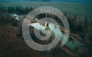 Aerial view of drying pond lake in secluded wooded area in cold autumn morning