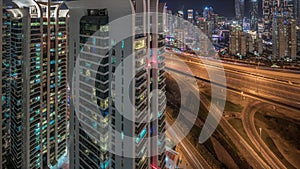 Aerial view of Dubai marina and JLT skyscrapers with glowing windows night timelapse with traffic on sheikh zayed road.