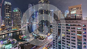 Aerial view of Dubai Marina residential and office skyscrapers with waterfront night timelapse