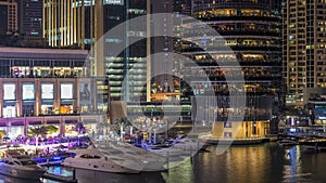 Aerial view of Dubai Marina with shopping mall, restaurants, towers and yachts night timelapse, United Arab Emirates.