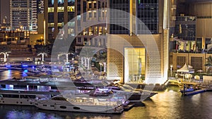 Aerial view of Dubai Marina with shopping mall, restaurants, towers and yachts night timelapse, United Arab Emirates.