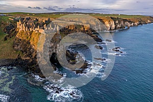 Aerial view with Dunluce Castle, the famous fortress in ruin in Northern Ireland UK, seen at sunrise