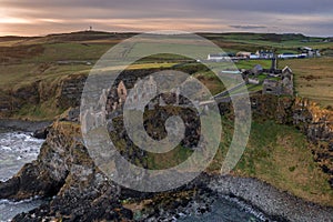 Aerial view with Dunluce Castle, the famous fortress in ruin in Northern Ireland UK, seen at sunrise