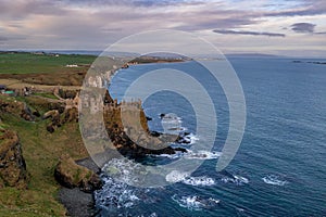 Aerial view with Dunluce Castle, the famous fortress in ruin in Northern Ireland UK, seen at sunrise