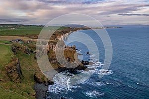 Aerial view with Dunluce Castle, the famous fortress in ruin in Northern Ireland UK, seen at sunrise