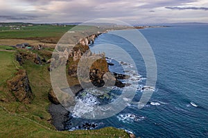 Aerial view with Dunluce Castle, the famous fortress in ruin in Northern Ireland UK, seen at sunrise