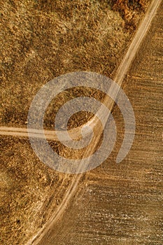 Aerial view of dusty dirt road through grassy plain landscape