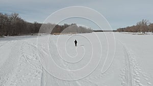 Aerial view an elderly woman engaged in Nordic walking with sticks in the winter forest. Healthy lifestyle concept