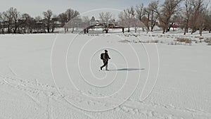 Aerial view an elderly woman engaged in Nordic walking with sticks in the winter forest. Healthy lifestyle concept