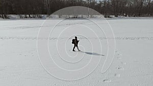 Aerial view an elderly woman engaged in Nordic walking with sticks in the winter forest. Healthy lifestyle concept