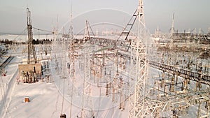Aerial view of an Electrical Substation in winter with high pylons and voltage distribution cables.
