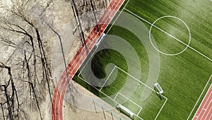 Aerial view of empty green football field with trees and their shadow