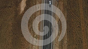 Aerial view on empty road in the desert or field in the middle of nowhere. Cinematic footage of 2 lanes motorway.