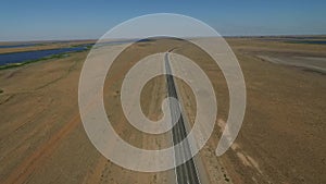 Aerial view on empty road in the desert or field in the middle of nowhere. Cinematic footage of 2 lanes motorway.