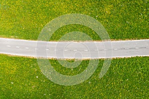 Aerial view of empty road in green meadows at sunny day