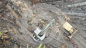 Aerial view of excavator digging the ground with a heavy bucket on a construction site. Heavy grader rakes soil. Drone view of pre