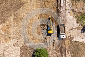 Aerial view of excavator loading sand into dump truck on construction site. top view from drone