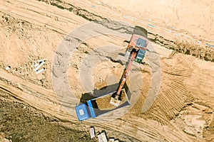 Aerial view of excavator moving ground and loading it in dump truck