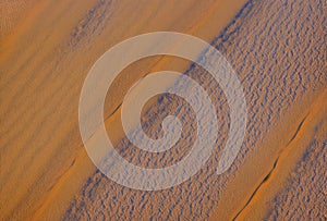Aerial view of expansive sandy desert dunes under clear blue skies. AI generated.
